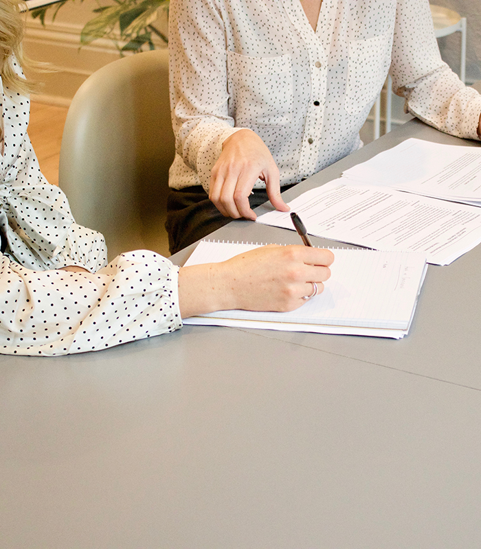 Two women reading and writing in a business meeting | Business Savers