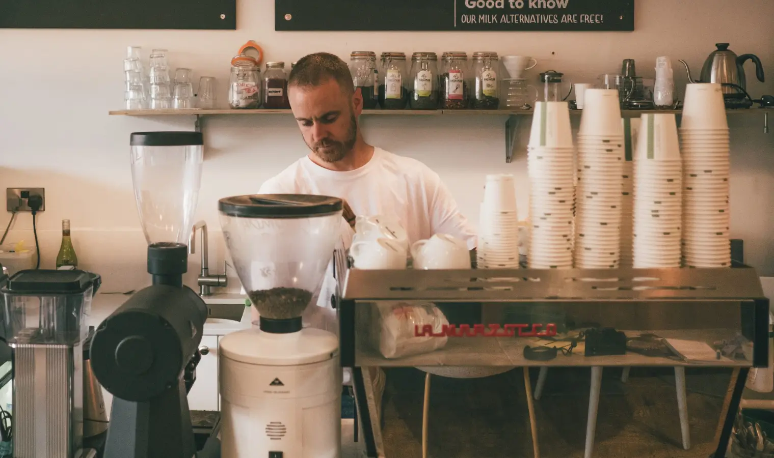 Barista behind coffee machine in cafe preparing coffee
