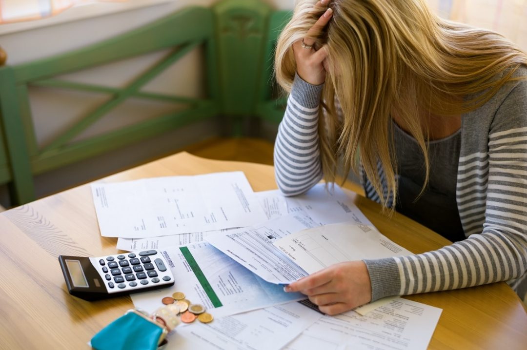 Woman at a table in shock with bills